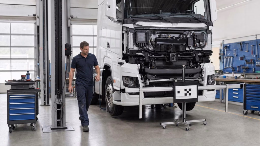 Mechaniker überprüft Sensor-Kalibrierung am Lkw-Fahrerhaus mit Target-Board auf Stativ.