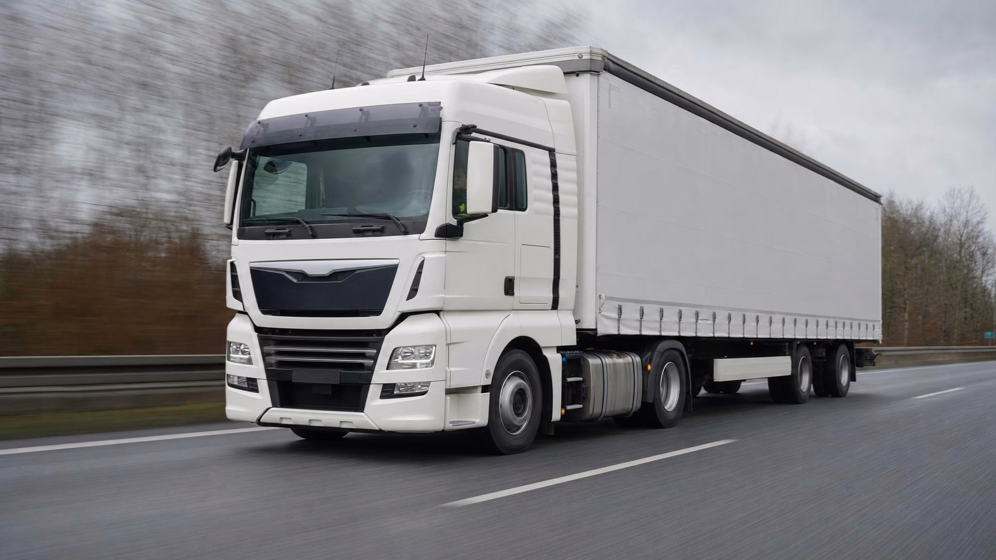 Hand in dunkelblauem Coverall hält Tankrüssel am seitlichen Tank eines Lkw an der Werkstatt-Tankstelle
