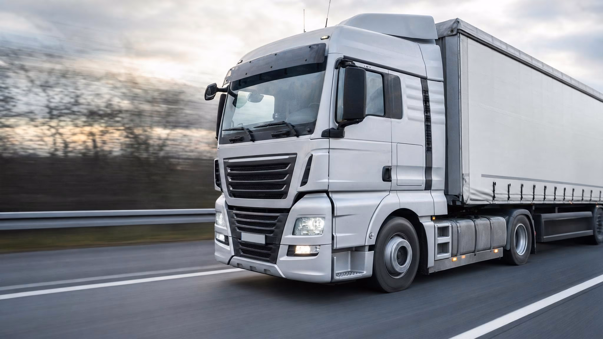 Werkstattmeister mit Klemmbrett steht vor einem fertig reparierten Lkw und trägt mit Stift einen Eintrag ins Wartungsheft ein