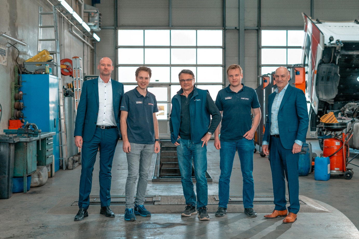 Norman Binde, Raffael Lasic, Vladimir Lasic, Benjamin Lasic und Homer Smyrliadis vor einem Lkw in der Werkstatthalle der LKW Lasic GmbH