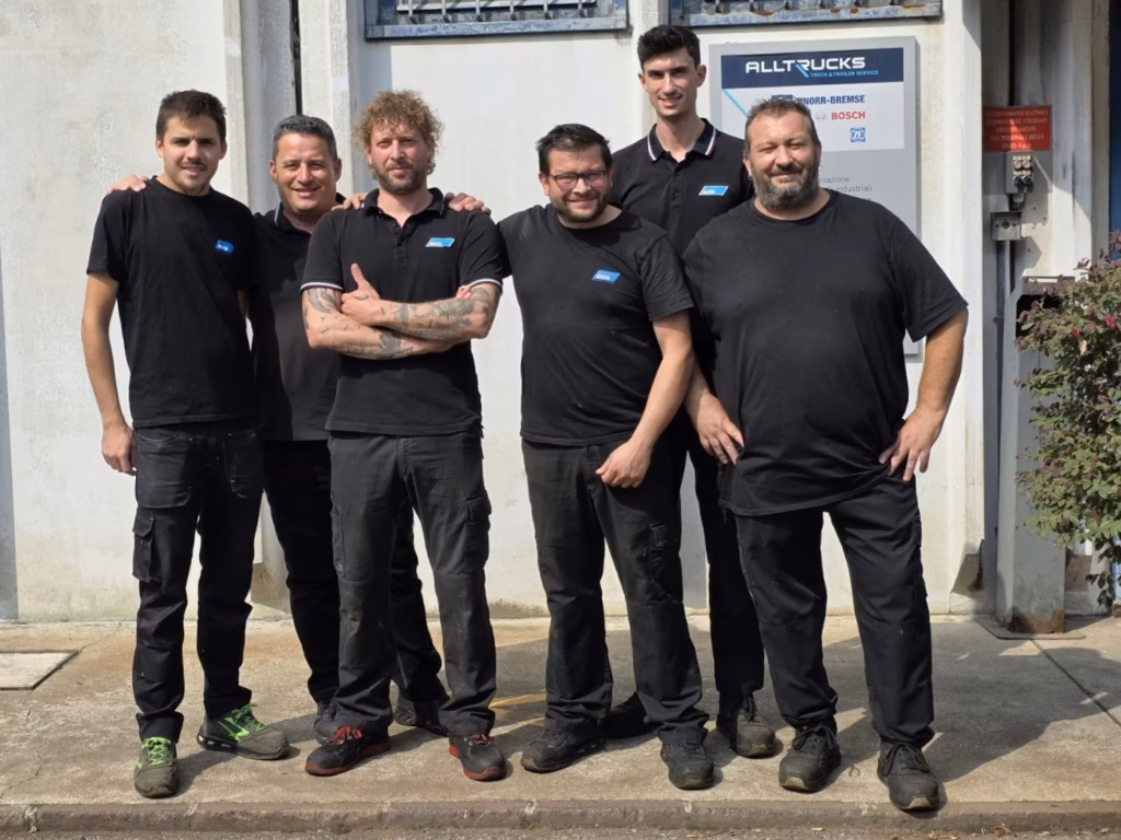 Sechsköpfiges Team von OVID S.p.A. in dunklen Alltrucks-Polos vor dem Werkstatteingang mit Alltrucks-, Knorr-Bremse- und Bosch-Logo