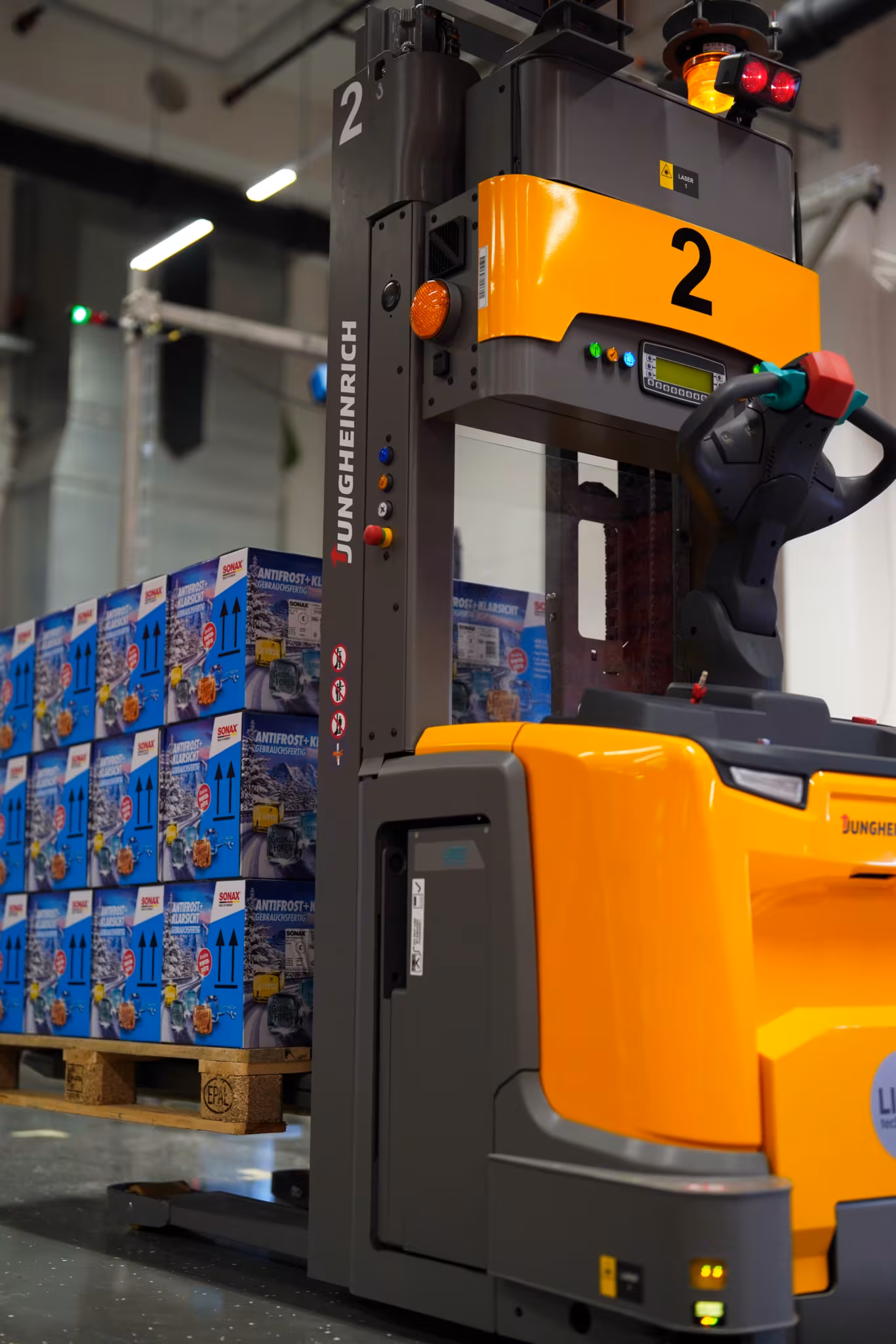 Un chariot de manutention automatisé transporte une palette de cartons Sonax dans le nouveau centre logistique