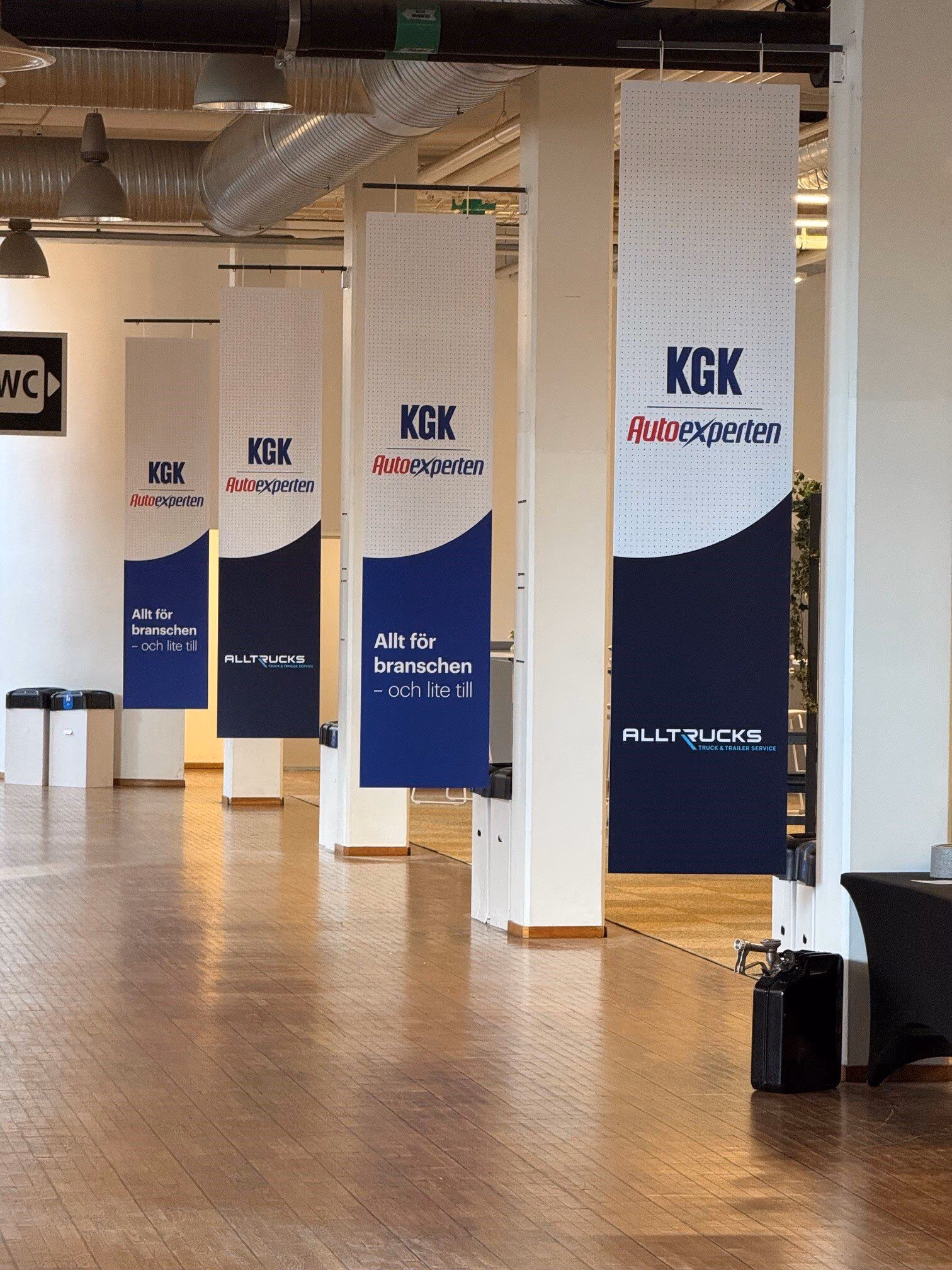 Carteles colgantes con los logotipos de KGK Autoexperten y Alltrucks en la zona de entrada de la feria Elmia Lastbil 2026 en Jönköping