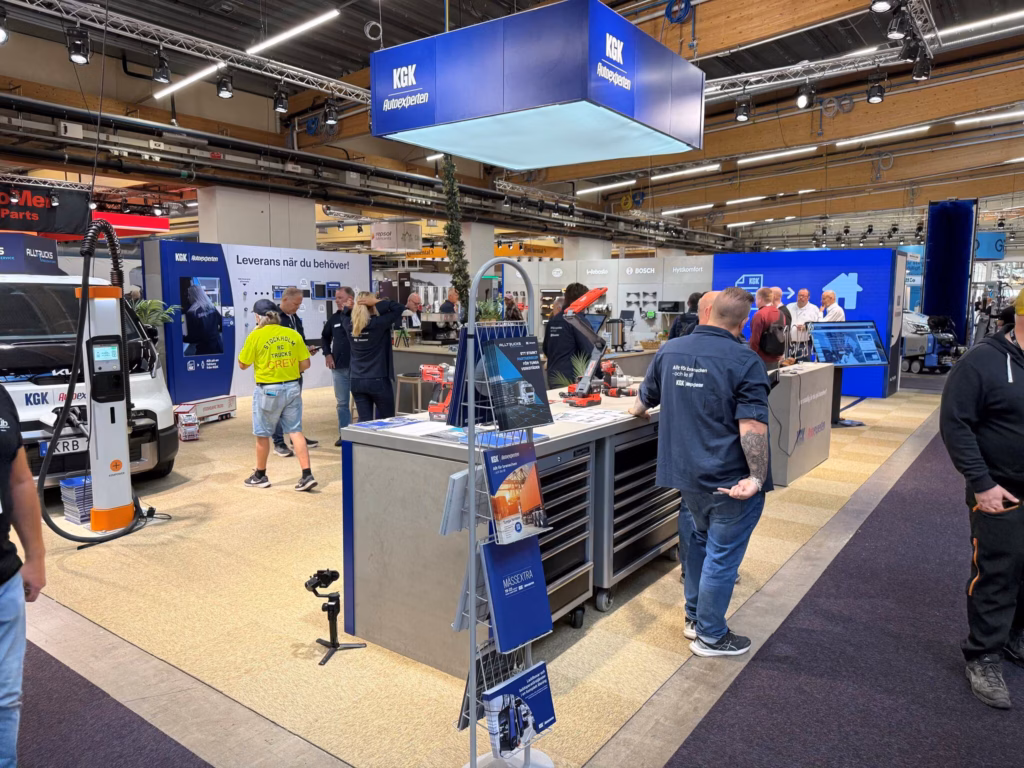 Stand de KGK Autoexperten en la feria Elmia Lastbil 2026 de Jönköping, con el cubo azul de KGK sobre el stand, el vehículo de taller y los visitantes charlando