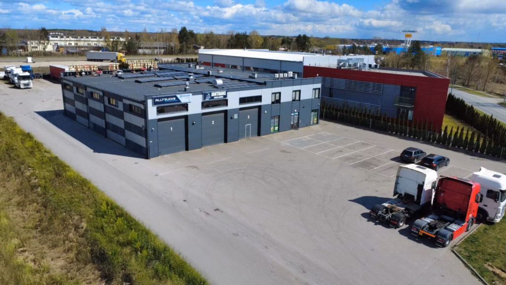 Vista aérea del taller de vehículos industriales Jantrans en Biała Podlaska, con las naves industriales, los logotipos de Alltrucks y Jantrans en la fachada y los tractores de remolque en el patio