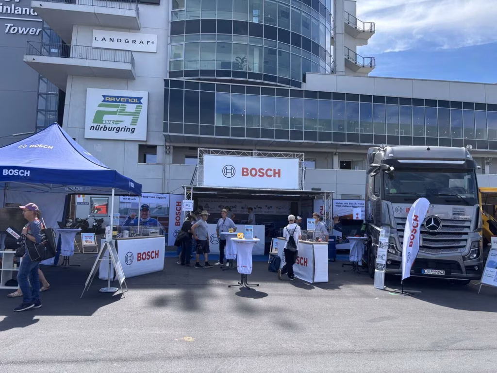 Stand de Bosch en el Truck Grand Prix 2026 en Nürburgring, con el portal de Bosch, mesas altas, un pabellón y un camión tractor Mercedes con adhesivos de Bosch delante de la tribuna